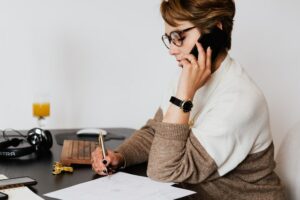 Woman taking notes about insurance rights while on phone call with car accident attorney